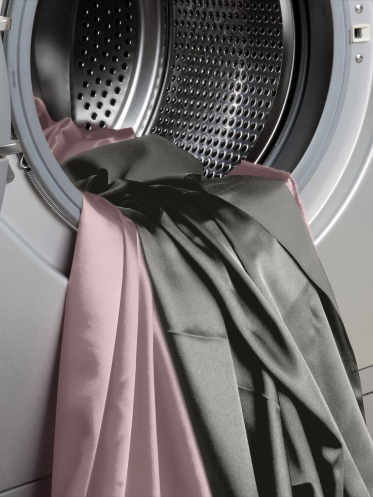Blush Pink and Obsidian Black silk bedding spilling out of an open washing machine drum